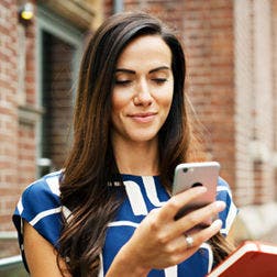 woman standing outside looking at a smartphone
