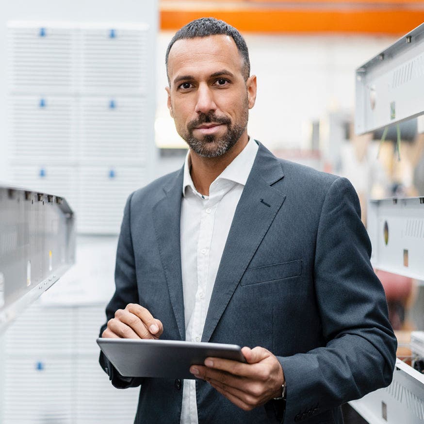 man in business suit using tablet in server farm